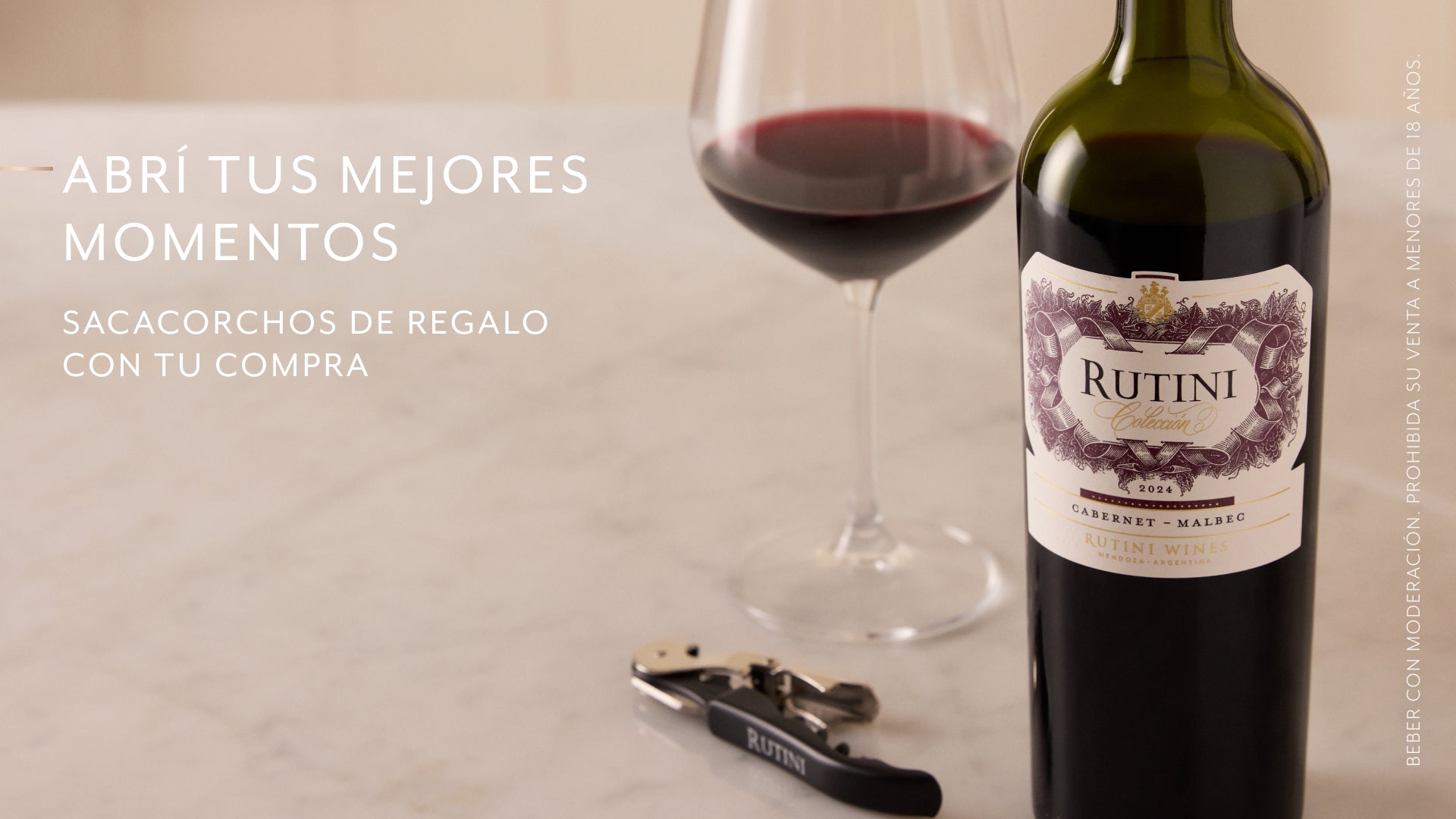 Botella de vino Rutini Colección Cabernet Malbec junto a una copa servida y un sacacorchos sobre mesa de mármol. Texto promocional: "Abrí tus mejores momentos. Sacacorchos de regalo con tu compra".